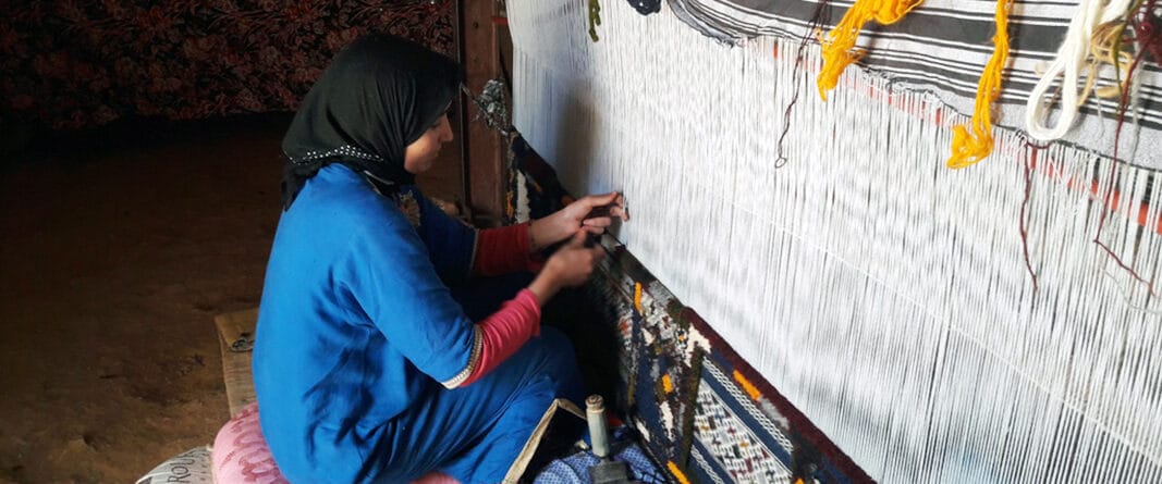 Berber Weaver on the weaving machine making moroccan rugs