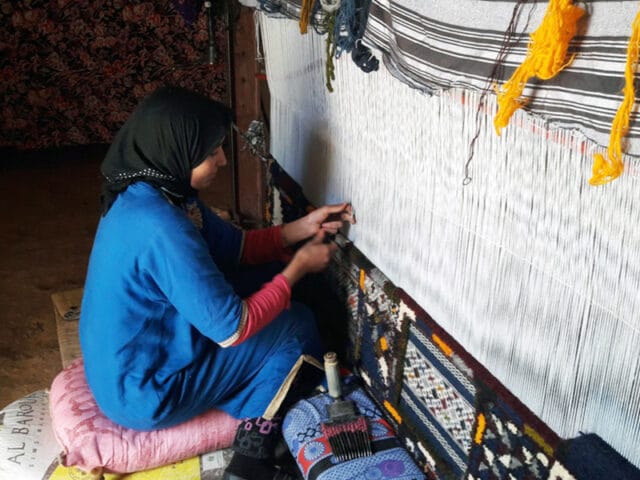 Berber Weaver on the weaving machine making moroccan rugs