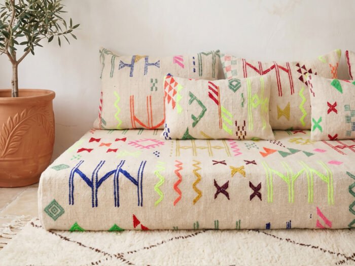 Colorful kilim floor sofa detail — cobalt zigzag, neon triangle, cross-mark motifs on ivory cream kilim weave