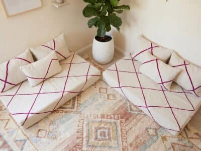 Overhead view of fuchsia diamond Berber floor sofa set on a vintage Moroccan rug beside a fiddle-leaf plant