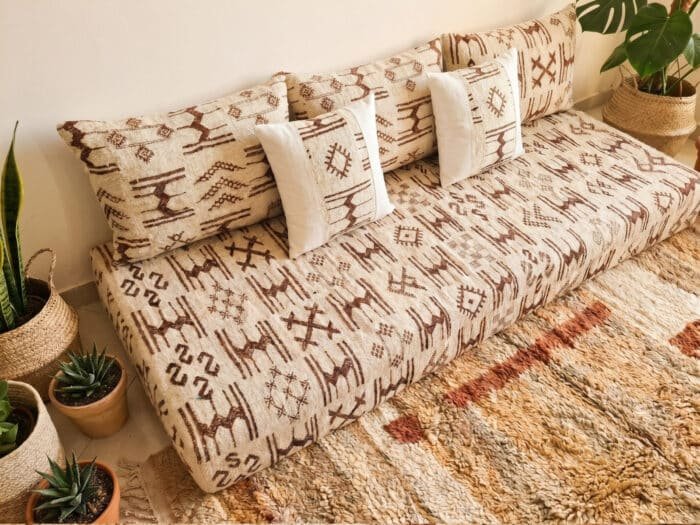 Ivory Azilal wool pile sofa close-up showing abstract brown Berber symbols and white linen accent pillows