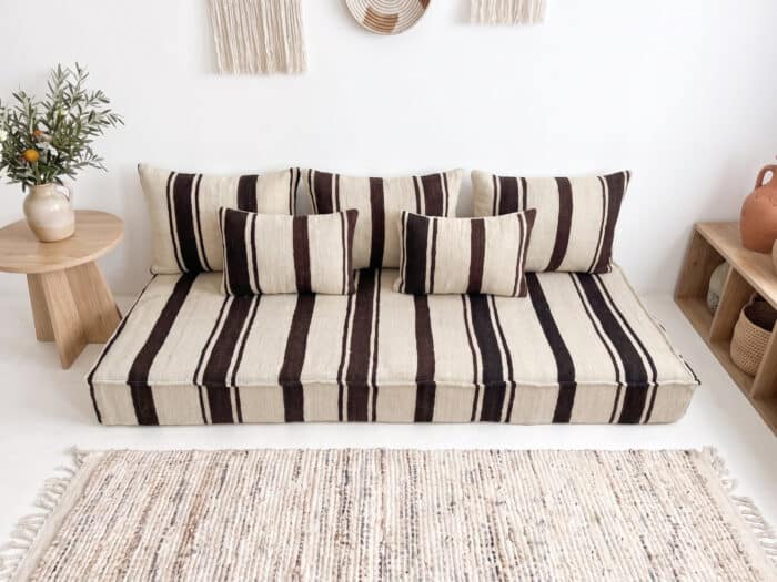 Brown striped kilim floor sofa styled with olive branches and terracotta pottery by Asala Living