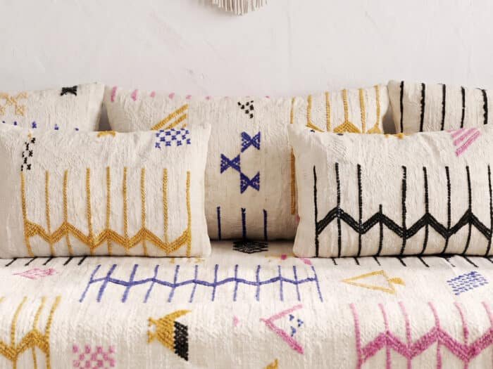 Cream floor sofa tribal motifs close-up, fuchsia and ochre Berber symbols on handwoven wool cushions