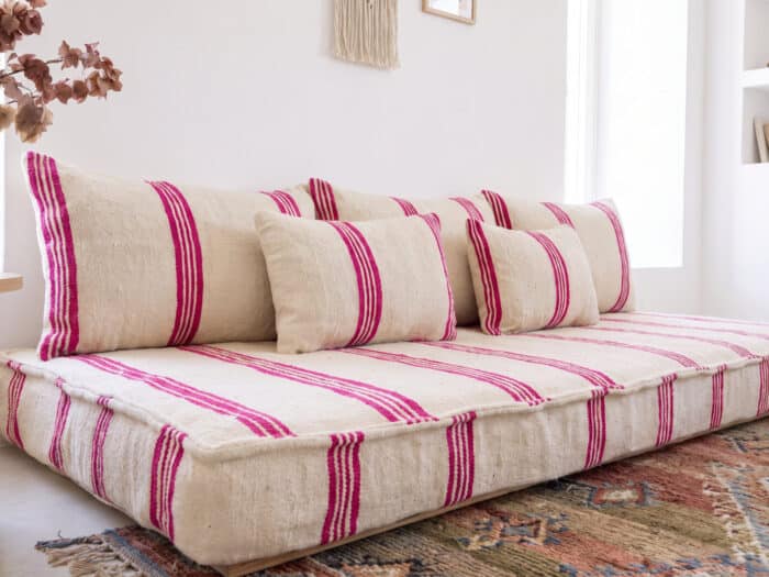 Ivory pink stripe floor sofa styled with five wool cushions beside a vintage Moroccan rug