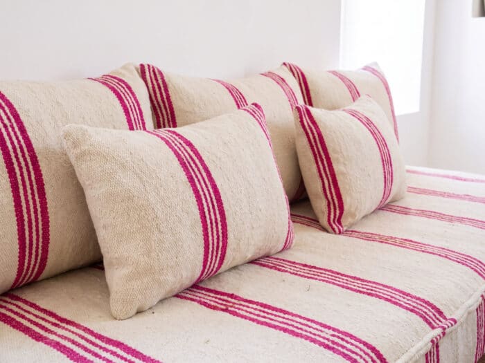 Ivory pink stripe floor sofa cushions in close view, magenta bands across handwoven Berber wool — Asala Living