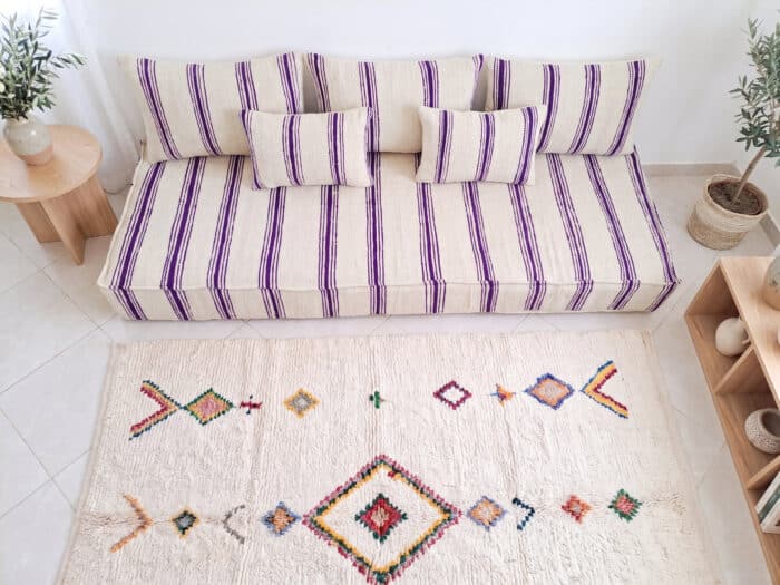 Overhead view of ivory wool floor sofa with violet stripes and five handwoven cushions, Asala Living