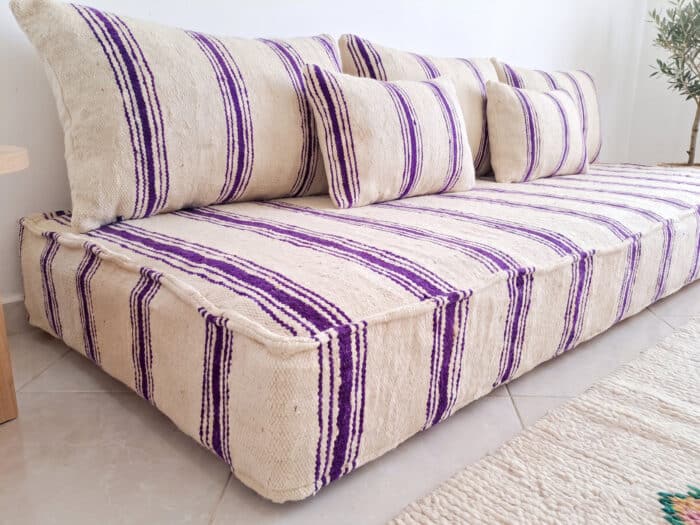 Close-up of ivory wool floor sofa with violet stripes showing flatweave texture and lumbar cushions