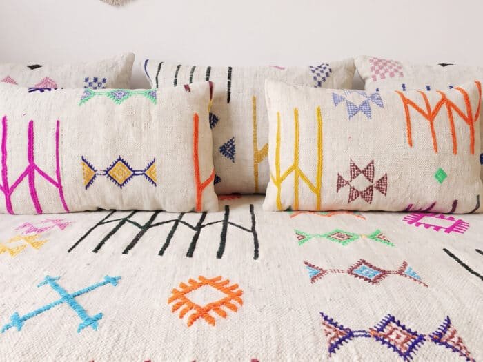 Close-up of Moroccan floor sofa with symbols, showing colorful Berber motifs and soft lumbar cushions