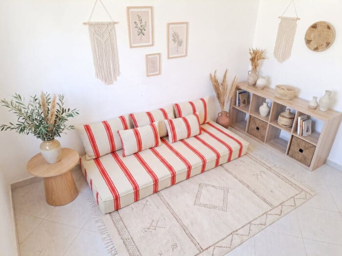 Orange stripe hanbel floor sofa seen at an angle showing back pillows and handwoven ivory wool surface