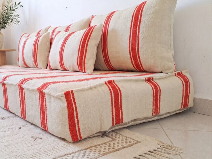 Close view of orange stripe hanbel floor sofa cushions with fine orange bands on flatweave ivory wool
