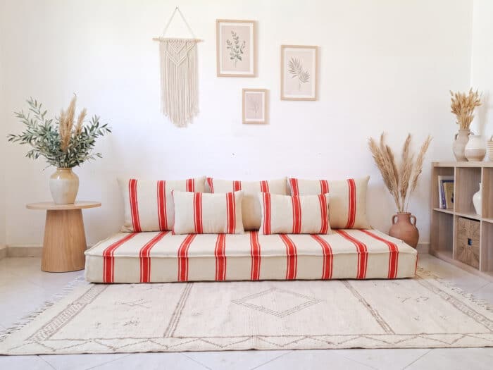 Orange stripe hanbel floor sofa in ivory wool styled with five pillows in a bright Moroccan living room