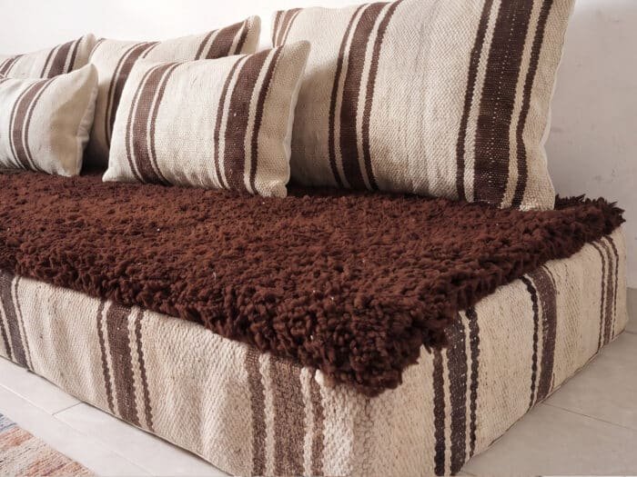 Brown shag floor sofa close-up showing plush chocolate wool pile and handwoven brown stripe detail