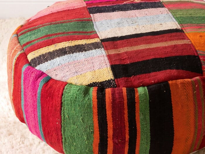 Close-up of Jewel Stripe Pouf showing patchwork panels of fine emerald, ruby and gold kilim stripes