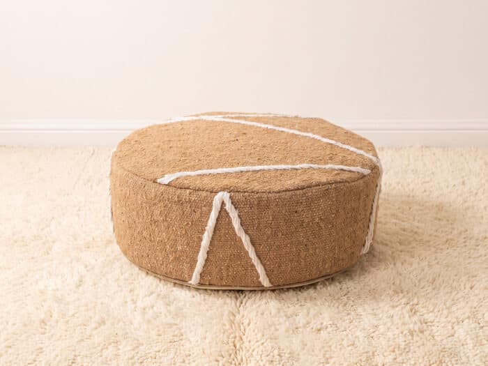 Morocco Beige Ottoman round cotton pouf styled on an ivory shag rug