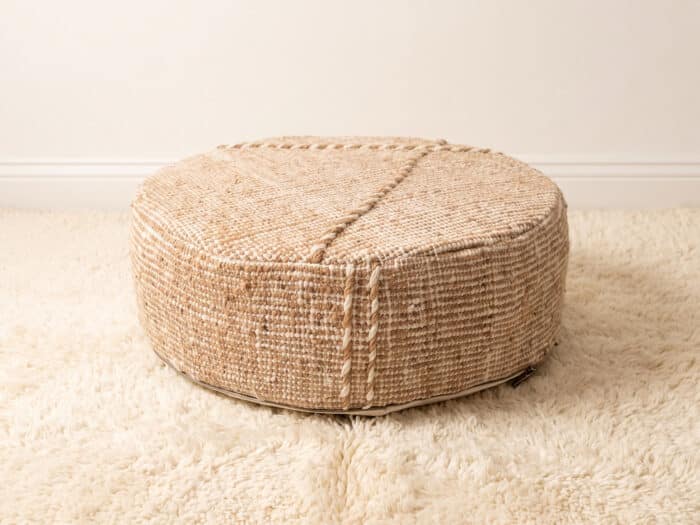 Morocco Beige Ottoman round cotton pouf styled on an ivory shag rug