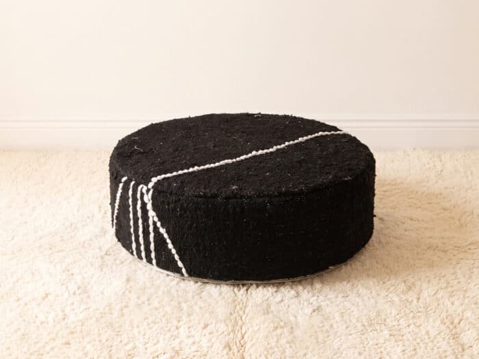 Morocco Black Ottoman round cotton pouf styled on an ivory shag rug