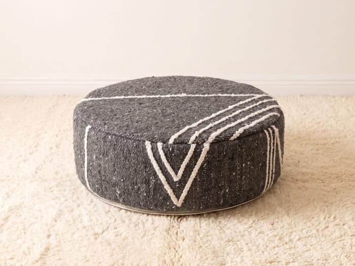 Morocco Dark Grey Ottoman round cotton pouf styled on an ivory shag rug