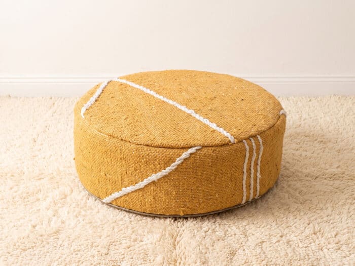 Morocco Yellow Ottoman round cotton pouf styled on an ivory shag rug