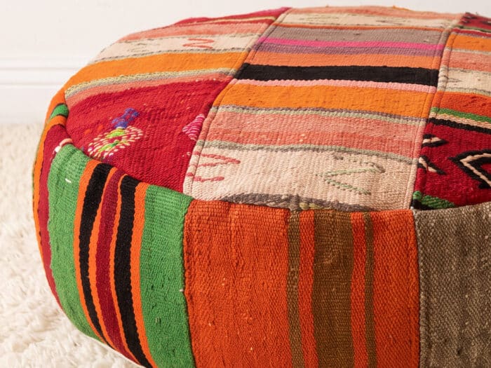 Close-up of Warm Stripe Pouf showing fine coral and peach kilim stripes with embroidered motifs