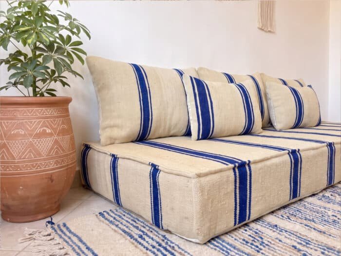Royal blue striped floor couch angled view beside a Berber terracotta planter and gallery wall