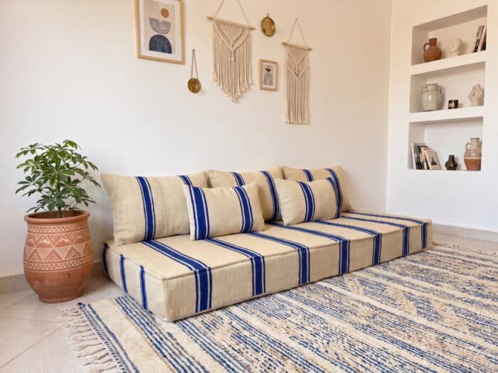 Royal blue striped floor couch styled with matching cushions on a blue Berber rug in a bright room