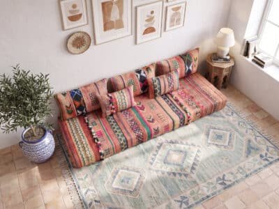Vintage terracotta floor sofa seen from above on a pale kilim rug with tribal stripe cushions