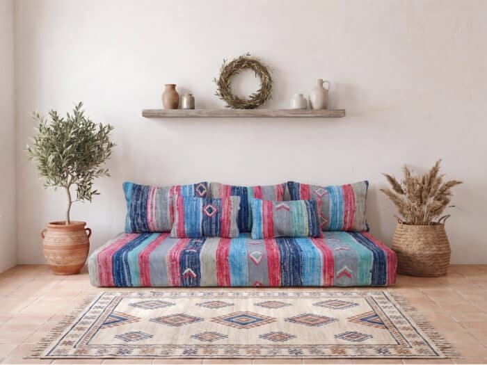 Blue and raspberry boucherouite floor sofa styled with a Berber rug and olive tree in a Moroccan room