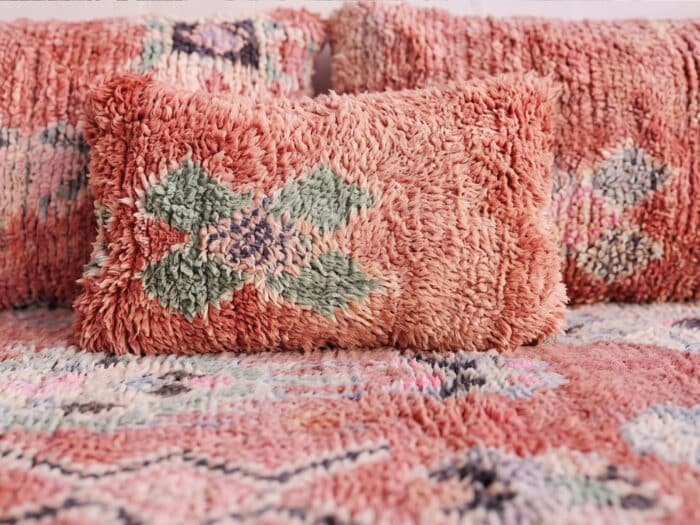 Blush pink shag floor sofa close-up, deep wool pile with a sage and rose Berber motif