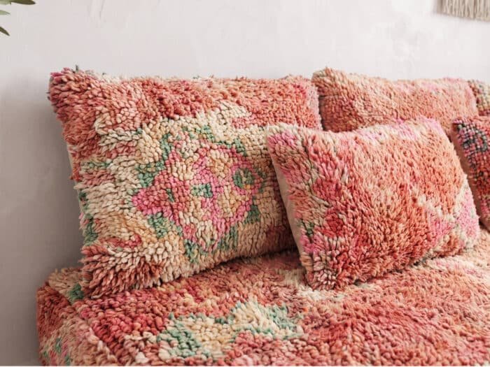 Salmon pink shag floor sofa close-up, deep coral wool pile with faded Berber floral motifs