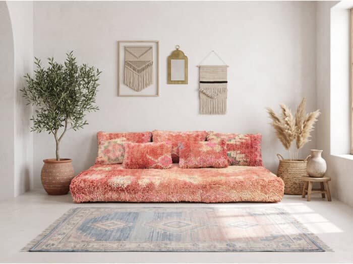 Salmon pink shag floor sofa styled below macrame and an olive tree in a boho Moroccan room