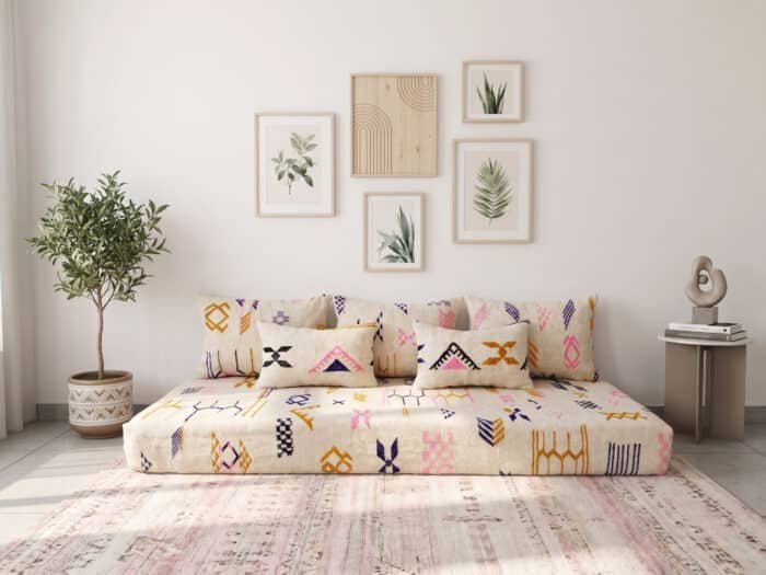 Amazigh symbol floor couch in cream wool with pink, mustard and indigo motifs, seen from above in a sunlit room