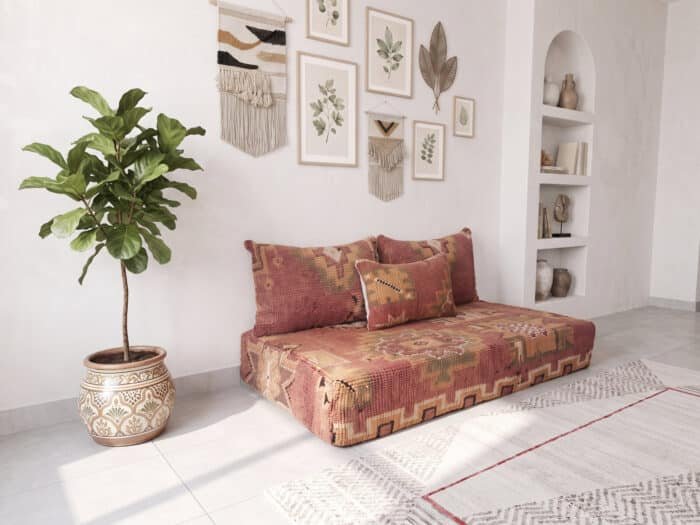 Brick red Berber floor sofa set against a white wall with fig tree and vintage wool lumbar pillow