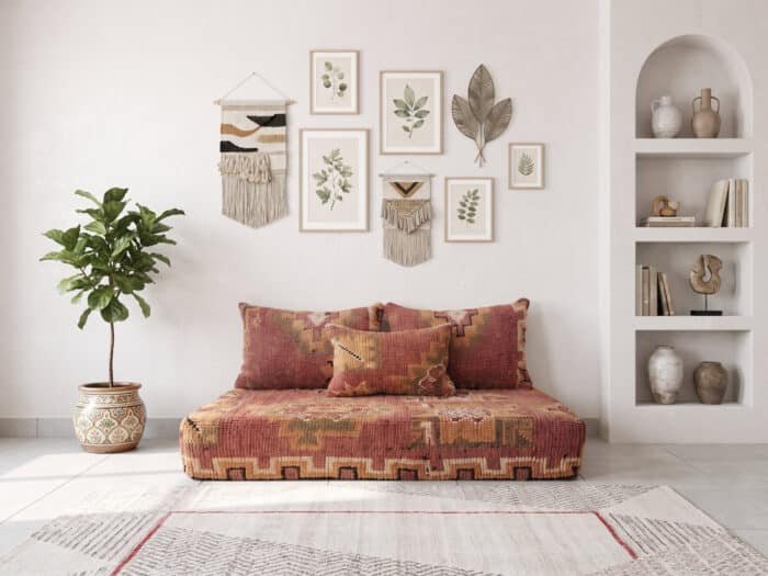 Brick red Berber floor sofa with ochre medallion pillows, top view in a bright room