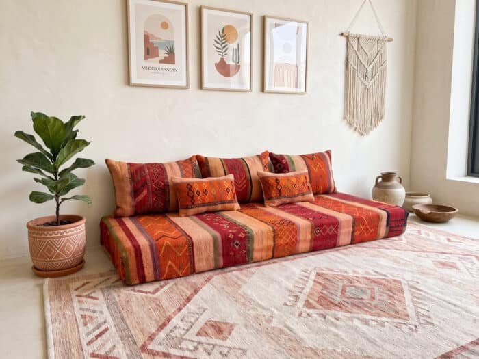 Orange and peach Berber floor seating set in a bright room with a pink rug and framed prints