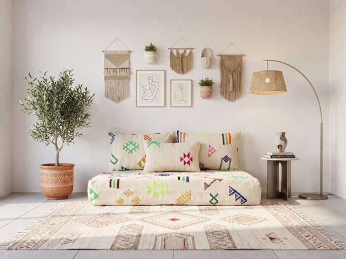 White majlis sofa in a sunlit room with olive tree, macramé gallery wall and arc lamp