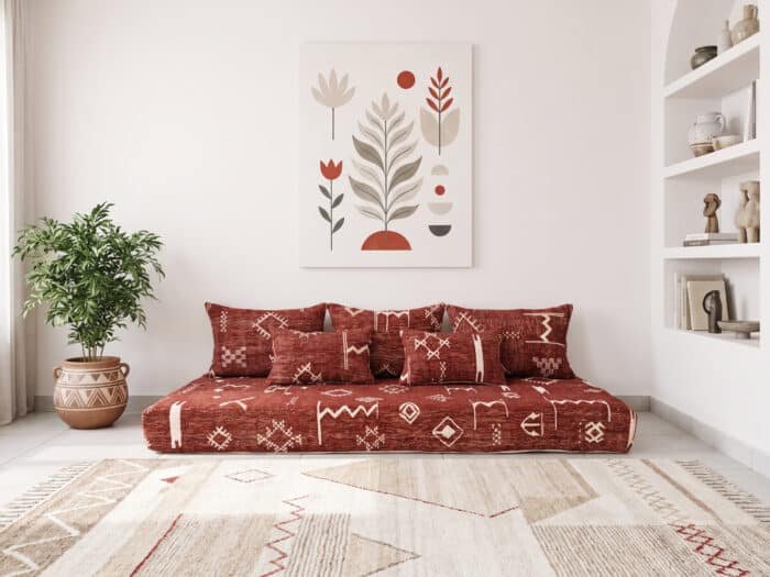 Burgundy floor sofa with ivory Berber glyphs and five matching pillows, front view in a white room