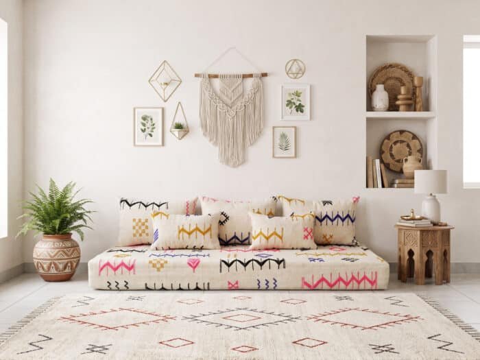 Ivory chevron floor couch against a white wall with macramé, fern and carved side table