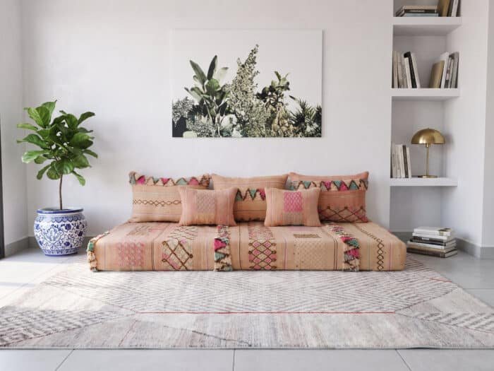 Peach floor couch front view beside a blue and white planter, fiddle leaf fig and botanical canvas