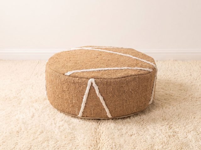 Morocco Beige Ottoman round cotton pouf styled on an ivory shag rug