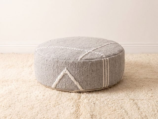 Morocco Light Grey Ottoman round cotton pouf styled on an ivory shag rug