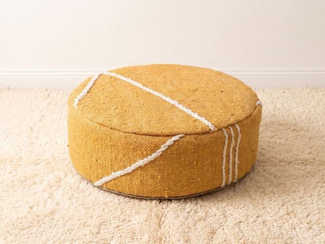 Morocco Yellow Ottoman round cotton pouf styled on an ivory shag rug