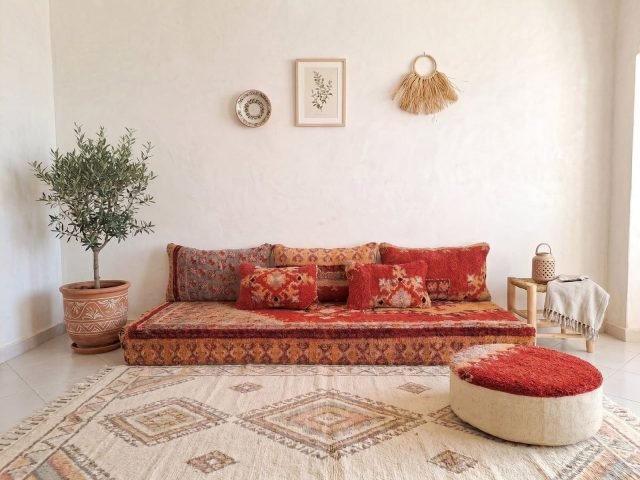 Vintage Boujaad red floor sofa set with crimson pile cushions on Berber rug, tadelakt wall